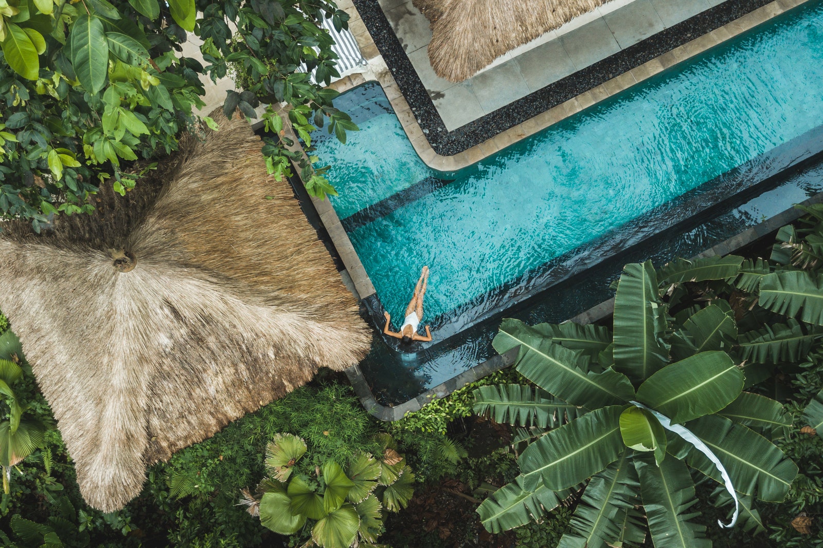 Girl relaxation in private swimming pool hiding in jungle. Wealth travel. Top view drone point of view directly from...